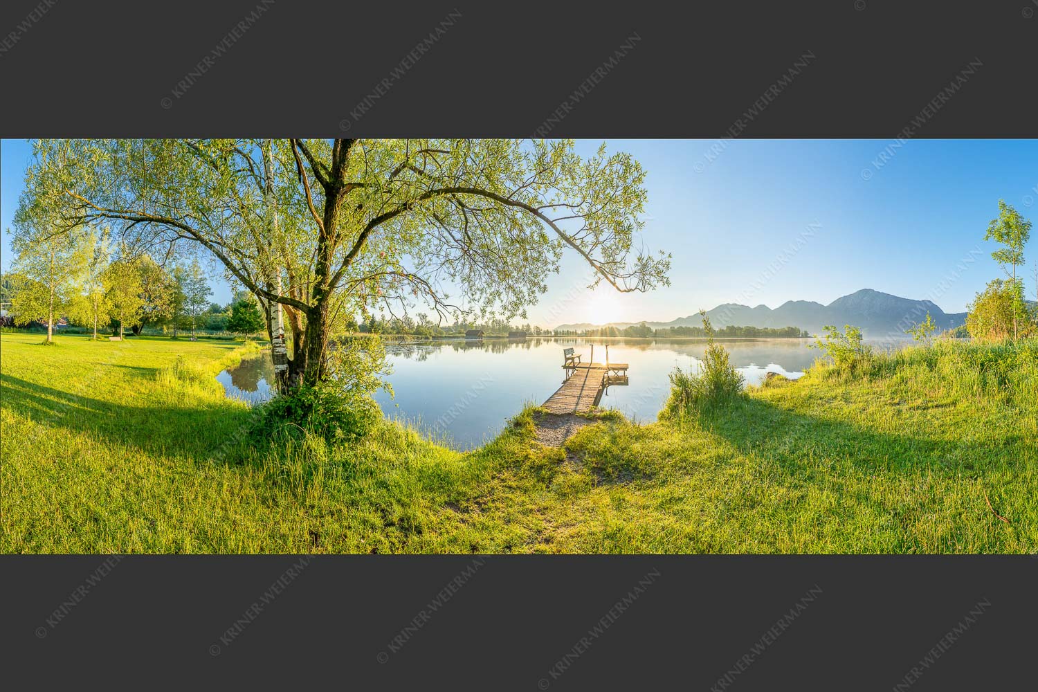 Blick über den Kochelsee bei Schlehdorf in den Sonnenaufgang - Die Sonne geht immer wieder auf III 2,5:1 -- Bootssteg mit Bank am Kochelsee - mehr Infos bei www.Kriner-Weiermann.de