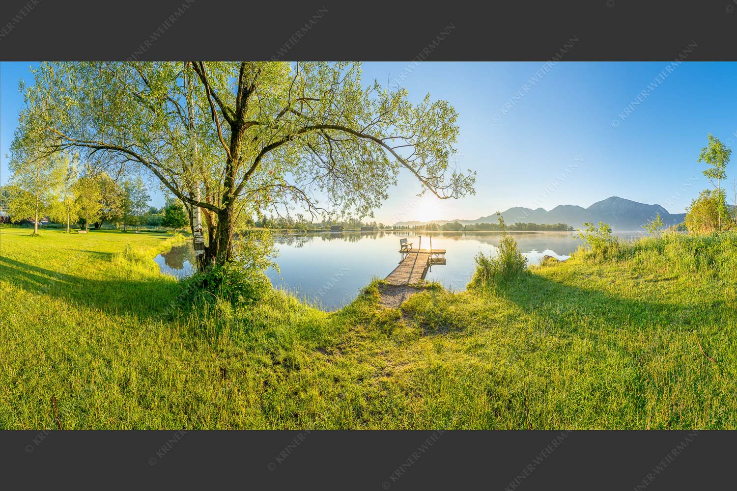 Blick über den Kochelsee bei Schlehdorf in den Sonnenaufgang - Die Sonne geht immer wieder auf III 2:1 -- Bootssteg mit Bank am Kochelsee - mehr Infos bei www.Kriner-Weiermann.de