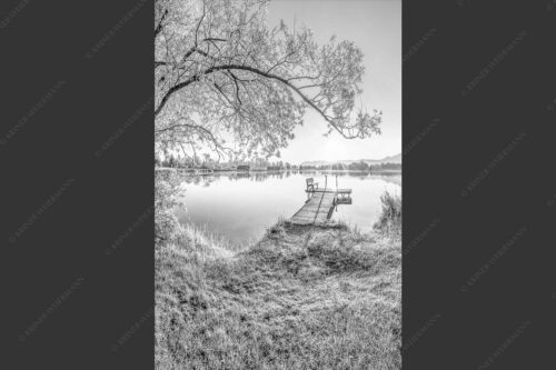 Blick über den Kochelsee bei Schlehdorf in den Sonnenaufgang - Die Sonne geht immer wieder auf III 2:3 sw -- Bootssteg mit Bank am Kochelsee - mehr Infos bei www.Kriner-Weiermann.de