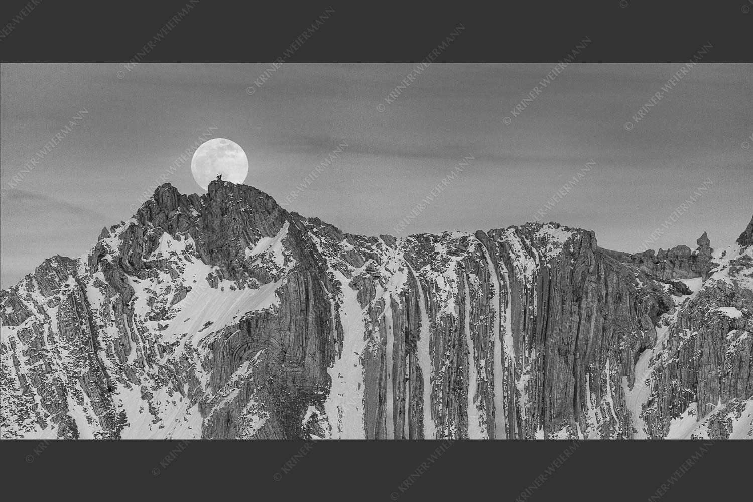 Der Vollmond wirkt riesig im Vergleich zu den beiden Menschen auf dem Gipfel - Verhältnis 2:1 sw -- Vollmond im Soierngebirge - mehr Infos bei www.Kriner-Weiermann.de