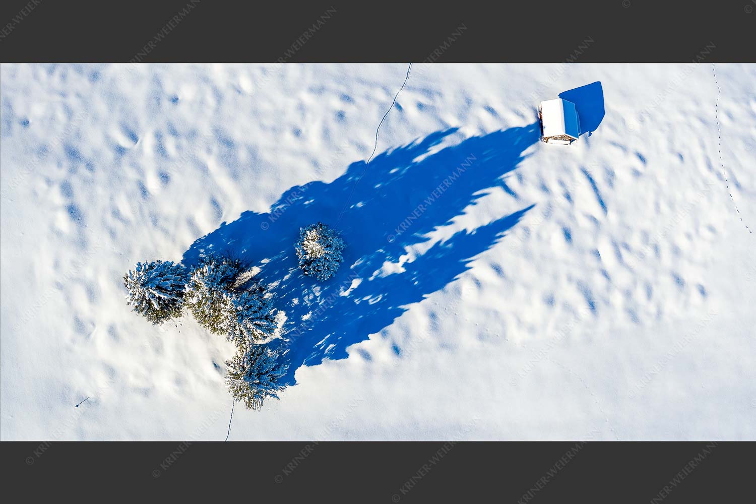 Blick auf eine Baumgruppe und Heustadel in Krün von Oben - Perspektive 2:1  -- Lange Schatten im Schnee - mehr Infos bei www.Kriner-Weiermann.de