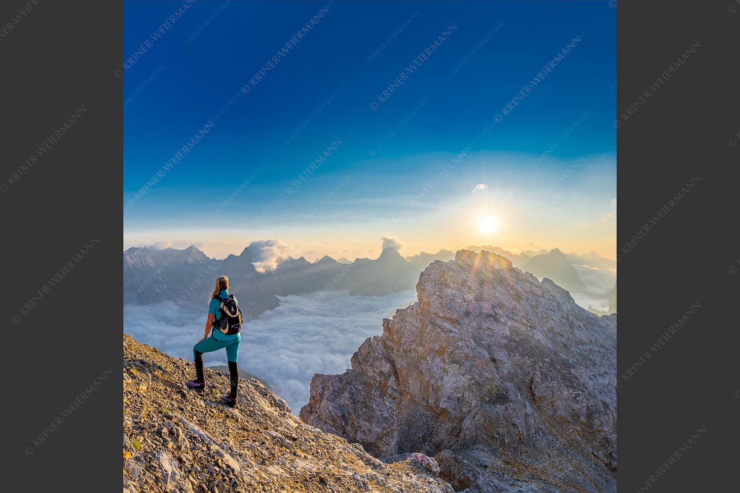 Blick von der Kaskarspitze im Karwendel über Nebelmeer in den Sonnenaufgang - Versteinert 1:1  -- Bergsteigerin auf Kaskarspitze im Karwendel - mehr Infos bei www.Kriner-Weiermann.de