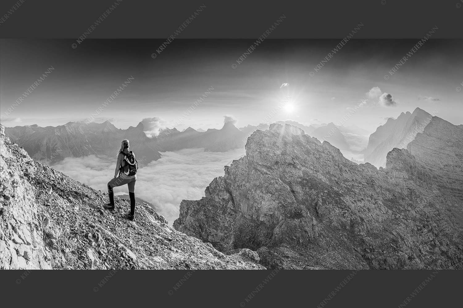 Blick von der Kaskarspitze im Karwendel über Nebelmeer in den Sonnenaufgang - Versteinert 2:1 sw -- Bergsteigerin auf Kaskarspitze im Karwendel - mehr Infos bei www.Kriner-Weiermann.de