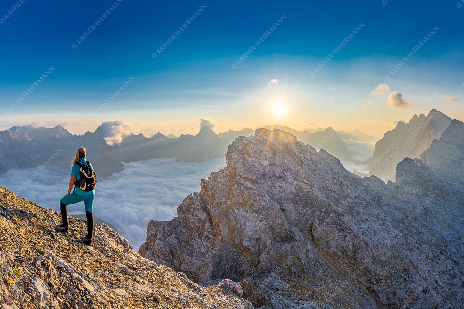 Blick von der Kaskarspitze im Karwendel über Nebelmeer in den Sonnenaufgang - Versteinert 3:2  -- Bergsteigerin auf Kaskarspitze im Karwendel - mehr Infos bei www.Kriner-Weiermann.de