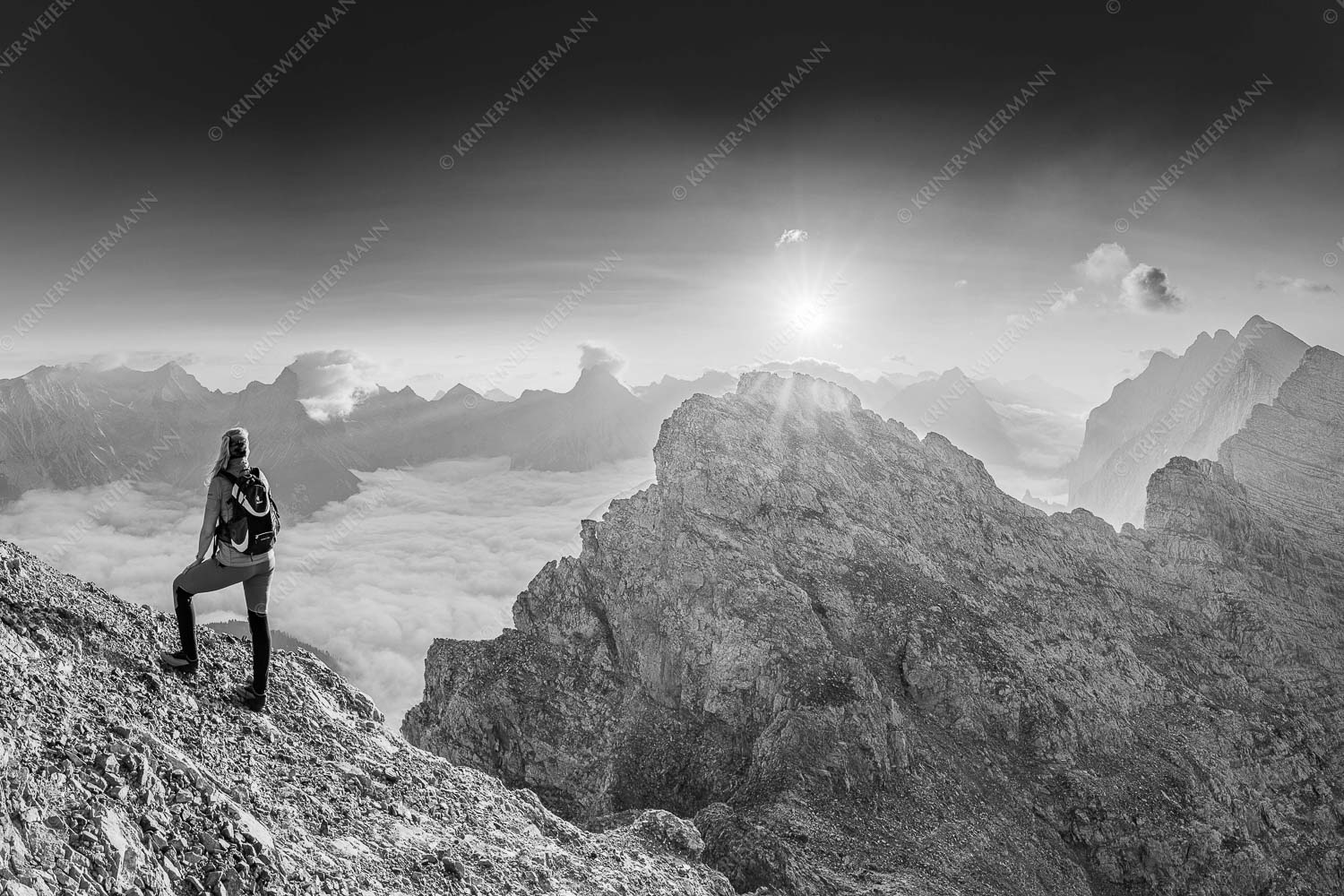 Blick von der Kaskarspitze im Karwendel über Nebelmeer in den Sonnenaufgang - Versteinert 3:2 sw -- Bergsteigerin auf Kaskarspitze im Karwendel - mehr Infos bei www.Kriner-Weiermann.de