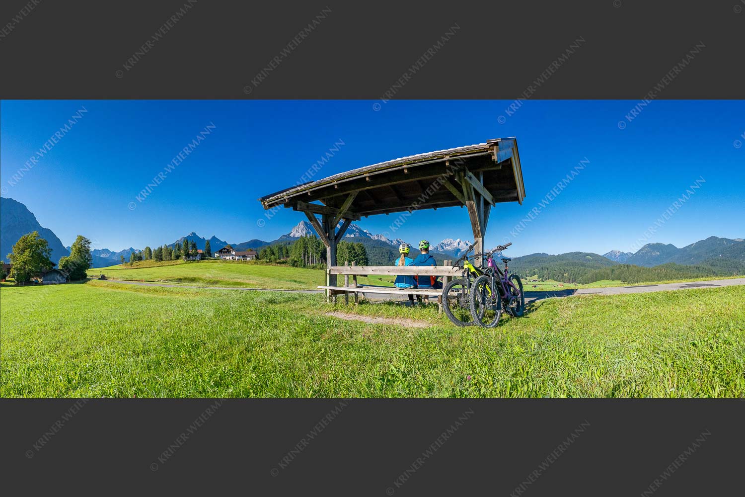 Rastbank am Tonihof mit Blick zum Wetterstein- und Estergebirge - Imposante Rast 2,5:1  -- Fahrradfahren in der Alpenwelt Karwendel - mehr Infos bei www.Kriner-Weiermann.de
