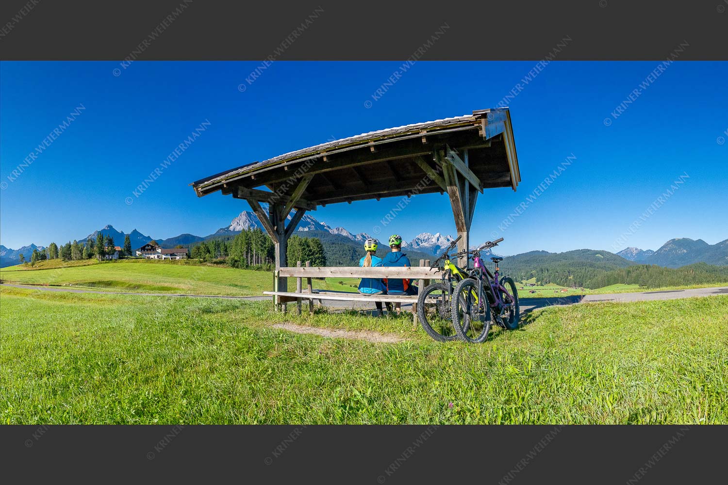 Rastbank am Tonihof mit Blick zum Wetterstein- und Estergebirge - Imposante Rast 2:1  -- Fahrradfahren in der Alpenwelt Karwendel - mehr Infos bei www.Kriner-Weiermann.de